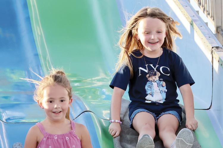 Paislee Stamper (left) and A.J. Western laugh while sliding down the sack race course