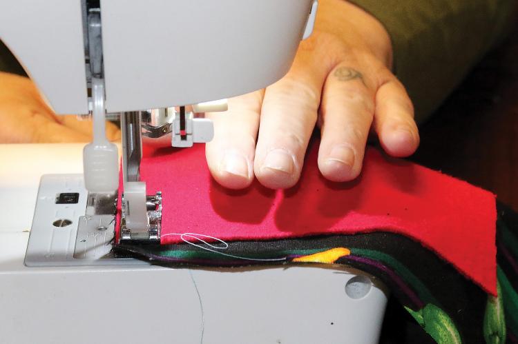 Richardson sews the back panel of a mask