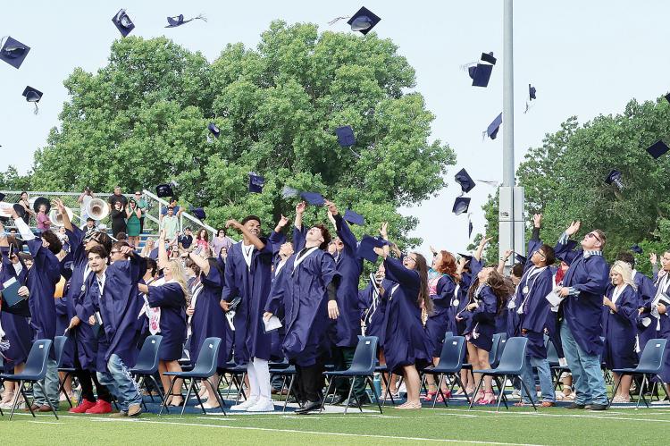 Graduates throw their caps into the air