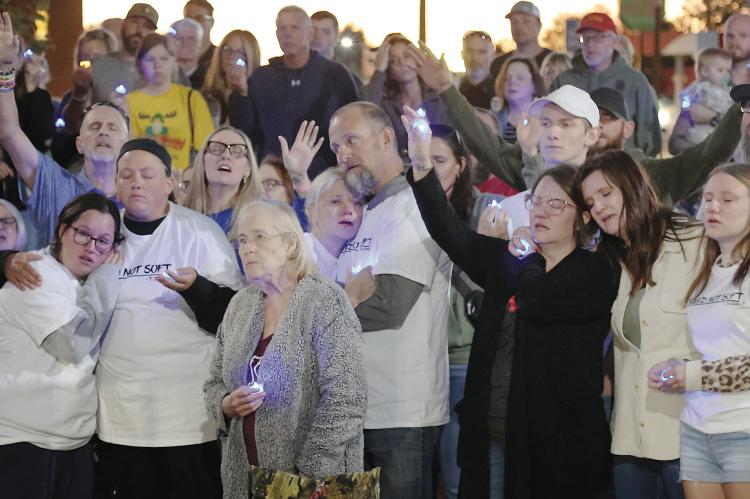 The Duran family (white shirts) pray with residents at the vigil
