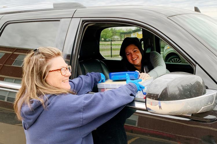Jorski hands homework to Maples outside Sacred Heart Catholic School