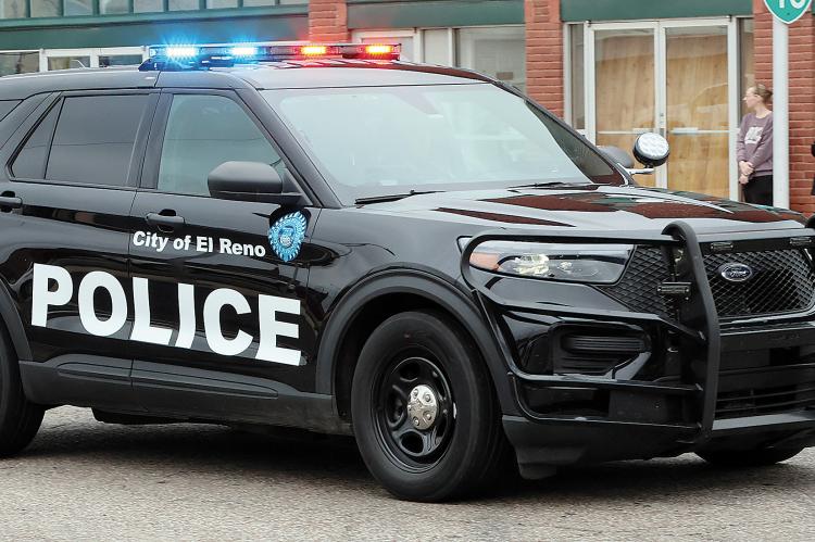Julie Ross-Martin (black jacket) covers her heart as an El Reno Police Department unit drives by