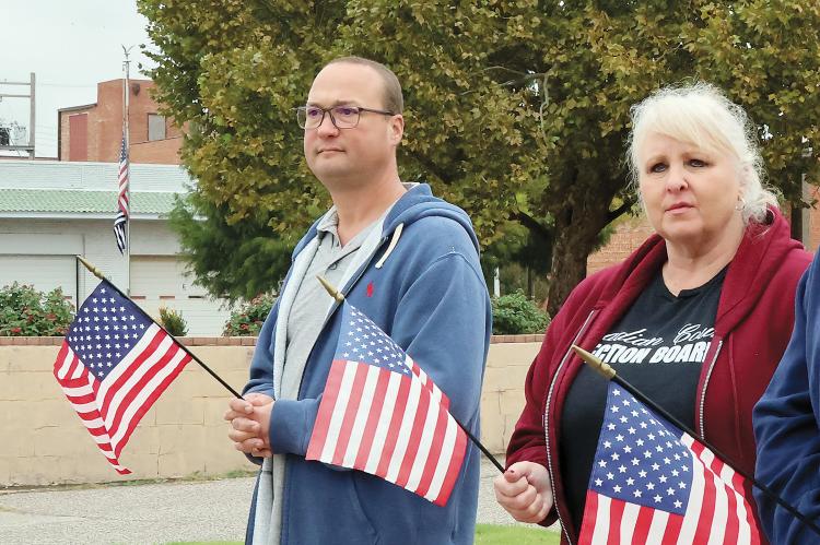 Allen Arnold and Angie Meyer hold American flags while watching the procession