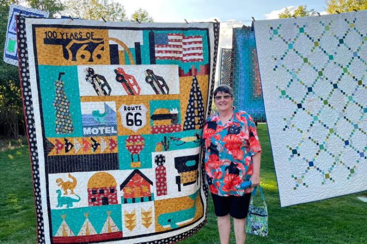 MaCrae Putnam next to her Route 66 quilt at the show in Utah