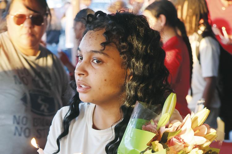 Antoinette Richey holds a bouquet of flowers and a lighted candle during the vigil