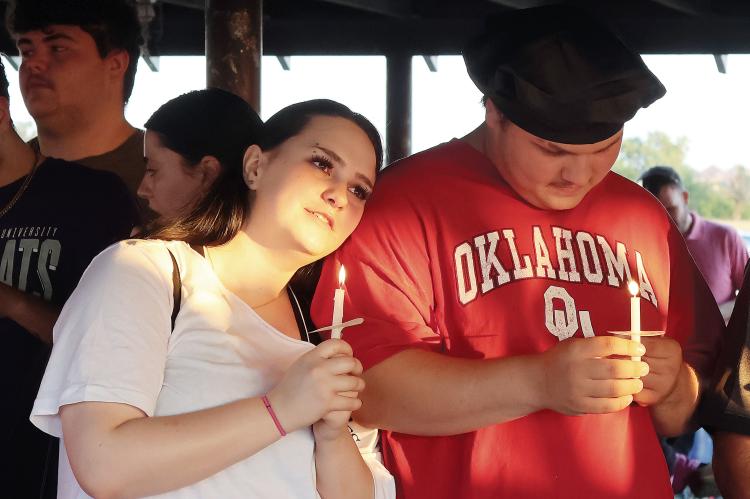 Two vigil attendees stand in silence with candles