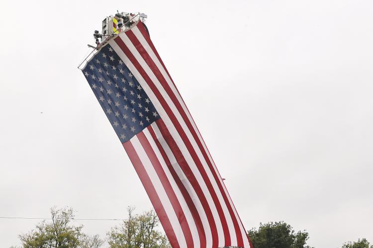 The hearse carrying Sgt. Thomas Duran’s body passes in front of a large American flag hoisted by the El Reno Fire Department