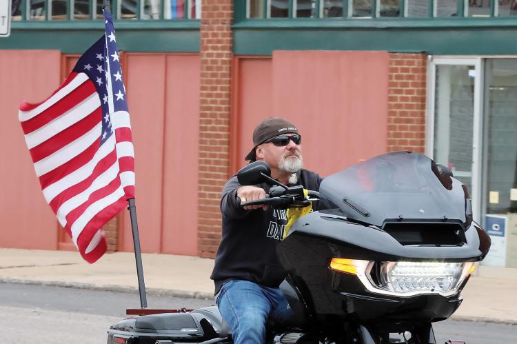 A motorcycle rider carries the flag in the line of vehicles