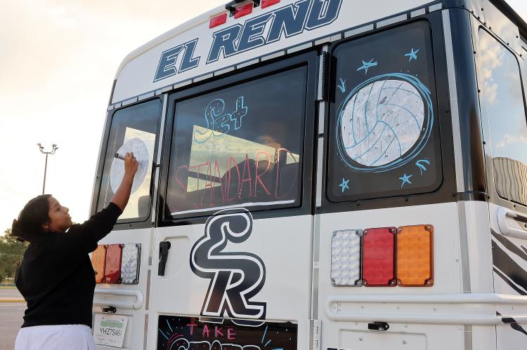 Kayla Trejo paints volleyballs on the back of the bus
