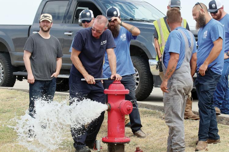 Jason Duff watches a spray of water shoot out of a hydrant along Jensen Road