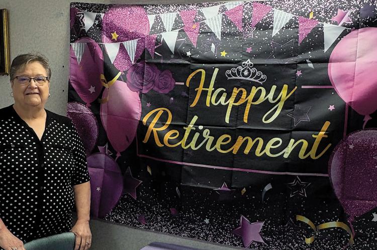 Becky Wahler stands next to her retirement party banner