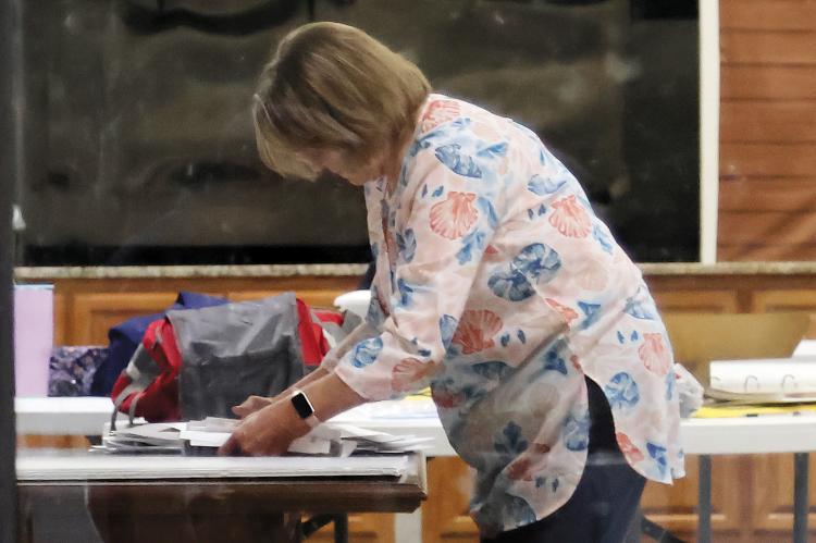 A precinct worker begins the closing process at a voting site