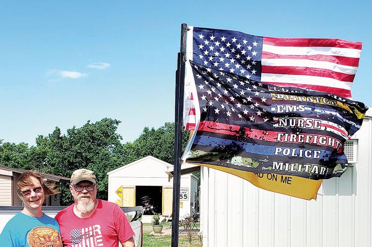 Floyd and Toni Mullens pose next to the flag that greeted first responders