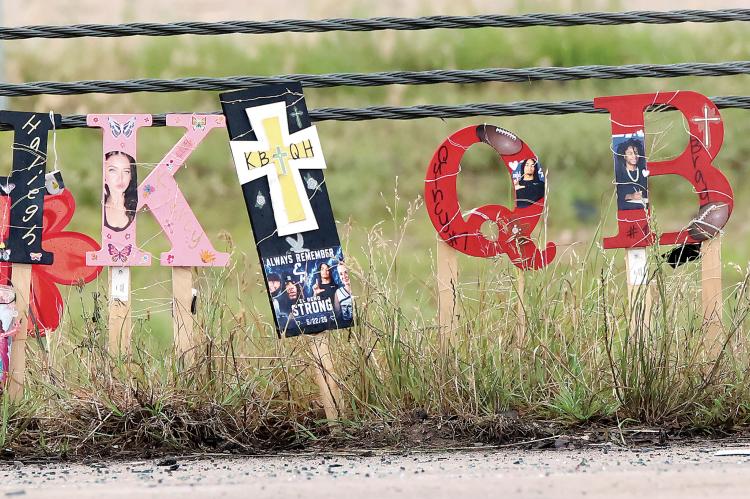 One of several roadside memorials at the collision site showing all four photos of those killed