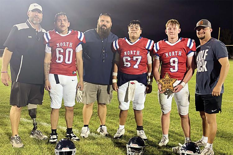 Omar Tristan (60), Jaron Youngbear (67) and Rustyn Cook (9) stand with the North Squad coaches