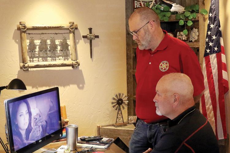 Chris West (seated) and Adam Flowers watch Roo Powell check her phone (on screen)