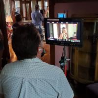 Director Tom Shell watches a monitor while giving direction to actors