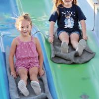 Paislee Stamper (left) and A.J. Western laugh while sliding down the sack race course