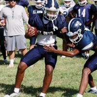 Brad Palmer tries to push off a defender during a tackling drill