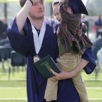 Graduate Zane Wilson helps his nephew Clyde try on his cap