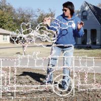 Ericka Nail adjusts Santa Claus’ hat on one of the light displays