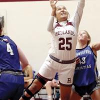 Jaylin Reveles splits a pair of defenders to get off a shot in the lane