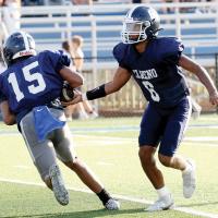 Elijah Fisher hands the football off to Kaleb Blackwolf on a running play