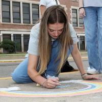 Bella Hart writes words in the center of a colorful rainbow