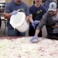 Matt Sandidge (far right) helps spread out onions on top of the hamburger meat