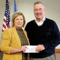 Steve Jensen hands an envelope to Donna Dyer of Blessing Baskets