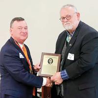 Jack Bryant receives a plaque from Ron Ramming to commemorate his induction