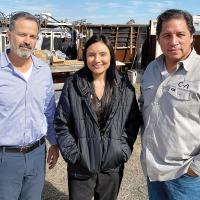 Aaron Hirsh, Kati Sullivan and Tony Maldonado stand in front of a corral where bison are being worked on at Concho