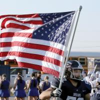 Cade Houston carries the American flag onto the field