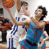 John Sandoval twists his body to avoid a Corn Bible Academy player while shooting