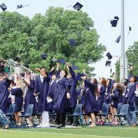 Graduates throw their caps into the air