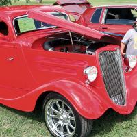 A young car enthusiast looks over this bright red 1934 Ford Coupe 