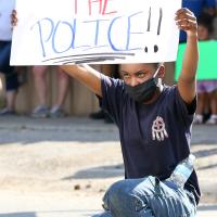Chyna Richey kneels while holding a sign
