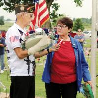 Nancy Salsman holds the microphone while Cliff Cagle of the VFW prepares to lay a wreath
