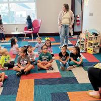 Children sit and listen as Bridget Scheffler reads them a story