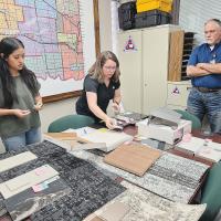 Adaly Guasso, and Tayler Thompson display samples of wall and flooring materials to Tomas Manske