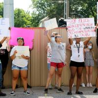 Protesters hold signs across the street from the El Reno police station
