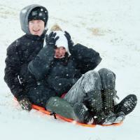 Davin Shamblin and Hannah Golish laugh as they sled down a hill