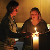 Debbie Maguire and her daughter Kaci light their candles