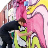 Dylan Bradway blends in a field of pink on a downtown alley wall