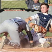 Gage Lesperance falls backward after being hit in the chest by an Elk City runner sliding headfirst into home