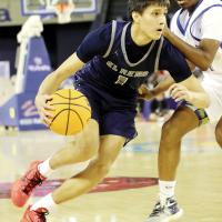 Carter Roman Nose drives the basketball around a Tulsa Memorial defender