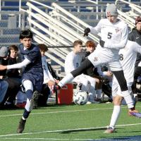 Carlos Conteras kicks the ball under a leaping defender