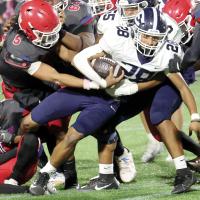 Jaydon Steele tries to free his ankle from a John Marshall tackler as he fights for extra yards