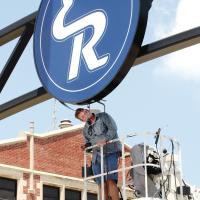 J.D. Lee looks over the electronics inside one of the 8-foot round lighted logo signs