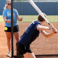 Head coach Kylee Webb throws to a batter during live hitting drills